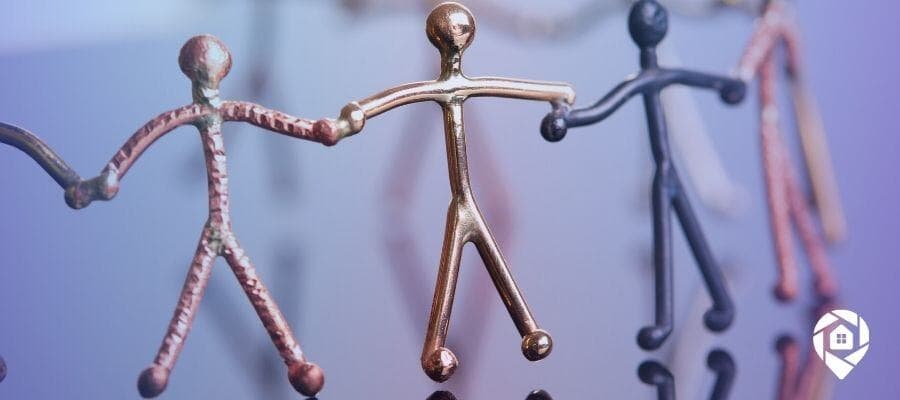 Metal stick figures holding hands, symbolizing teamwork and strong real estate investing connections.